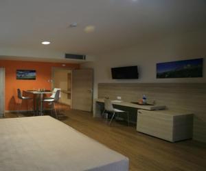 um quarto com cadeiras e mesas e uma televisão na parede em Turin Airport Hotel & Residence em San Francesco al Campo