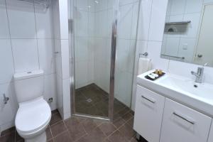 a bathroom with a shower and a toilet and a sink at City Gardens Apartments in Darwin