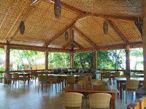 a dining area with tables and chairs in a building at Magic Oceans Dive Resort in Anda