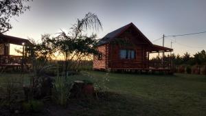una cabaña de madera en un patio con la puesta de sol en el fondo en Cabañas SOLANAS en San José