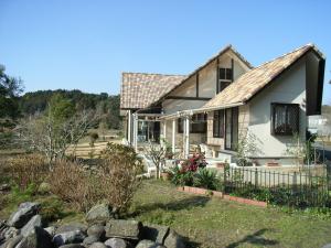 una casa blanca con una valla en un patio en Minshuku Hoshi no Sumika, en Shibushi