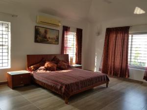 a bedroom with a large bed with red curtains at Elysium Kovalam in Chennai