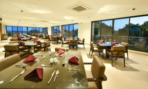 a restaurant with tables and chairs and large windows at K Hotels Entebbe in Entebbe