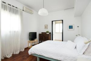 a white bedroom with a bed and a television at Eshkol Housing Carmel Center: Forest retreat in Haifa