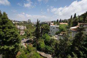 a view of a city with trees and buildings at Eshkol Housing Carmel Center: Forest retreat in Haifa