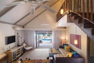 a living room with a couch and a staircase at Taj Coral Reef Resort & Spa - Premium All Inclusive with Free Transfers in North Male Atoll