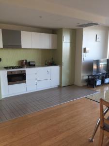 uma cozinha vazia com armários brancos e um fogão em GlenelgApt em Adelaide