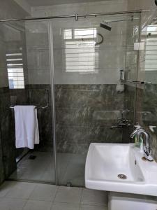 uma casa de banho com um chuveiro e um lavatório. em Clyford Suites em Bangalore