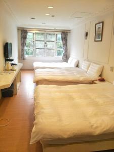 una camera d'albergo con 2 letti e una scrivania di Maria Hotel a Zhongzheng