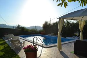 a swimming pool with an umbrella and chairs next to it at Agriturismo Montorso in Monte Rinaldo