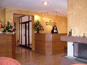 a woman standing at a reception desk in a lobby at Family Hotel Emaly 1 in Bankya