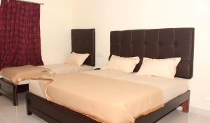 a bedroom with two beds and a red curtain at Abirami Residency in kāraikāl