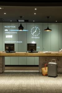 a lobby with a counter with a clock and a suitcase at ibis Berlin City Potsdamer Platz in Berlin