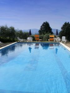 a large blue swimming pool with chairs and tables at Agriturismo Il Palazzaccio in Galliano