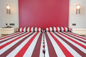a bedroom with a red and white striped bed at Hotel Adiafa in Barbate
