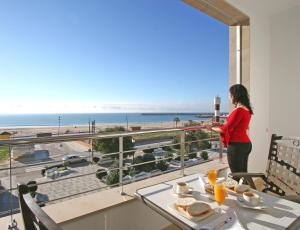 a woman standing on a balcony looking out at the beach at Hotel Adiafa in Barbate