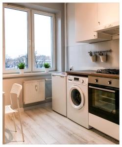 a kitchen with a stove, refrigerator and a window at Apartament Mikołajek Stare Miasto in Toruń