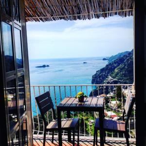 een tafel en stoelen op een balkon met uitzicht op de oceaan bij B&B Mamma Rosa Positano in Positano