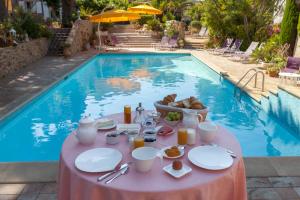 a table with food next to a swimming pool at L' Escapade Hôtel & Restaurant in Le Pradet
