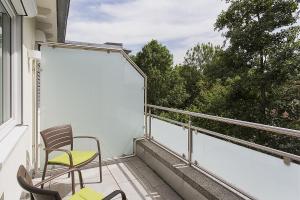 balcón con 2 sillas y ventana en Taome Feng Shui Stadthotel Breisgau, en Emmendingen