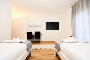 2 letti in una camera bianca con televisore di Gästezimmer Hurem a Kapfenberg