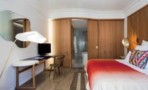 a bedroom with a bed and a desk with a television at Hôtel Vernet Champs Elysées Paris in Paris