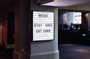a sign on the wall of a hotel room with the words stay safe eat cake at Malmaison Hotel Leeds in Leeds