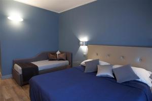 a blue room with two beds and a chair at Hotel Corso Alaxi Hotels in Alassio +40 photos