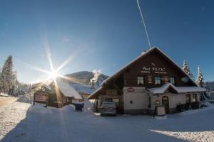 a ski lodge in the snow with the sun behind it at Pension Ploc in Harrachov