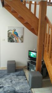 a living room with a tv and a staircase at Gîte La Cavée in Le Bourg-Dun