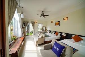 une chambre d'hôtel avec deux lits et un canapé dans l'établissement HA Devan Hoian Pool Villa, à Hội An