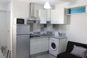 eine Küche mit weißen Schränken, einer Waschmaschine und einem Trockner in der Unterkunft Temporary Alicante HM in Alicante