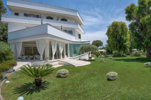 a large white house with a lawn in front of it at Il San Francesco Charming Hotel in Sabaudia