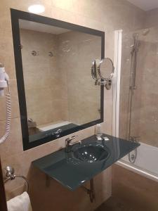 y baño con lavabo y espejo. en Hotel Familia Conde en Huelva