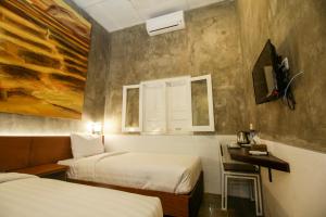 a hotel room with two beds and a tv at Watu Agung Guest House in Borobudur