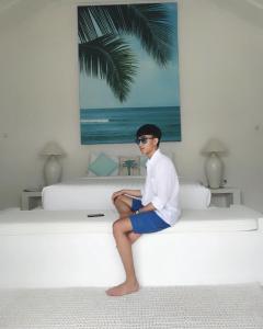 a man sitting on top of a bed at Harmony Villas in Kuta Lombok