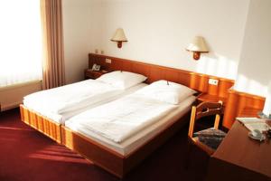 a bedroom with a large bed and a table and a desk at Hotel Blocksberg in Wernigerode