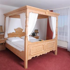 ein Schlafzimmer mit einem hölzernen Himmelbett mit weißer Bettwäsche in der Unterkunft Hotel Blocksberg in Wernigerode