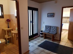 ein Wohnzimmer mit einem blauen Stuhl und ein Badezimmer in der Unterkunft Ferienwohnung Rosita in Langgöns