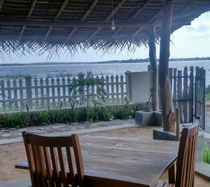 stół z krzesłami, płot i woda w obiekcie Great Lake Villa w mieście Tissamaharama