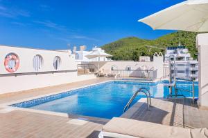 een villa met een zwembad en een parasol bij Aparthotel Duquesa Playa in Santa Eularia des Riu