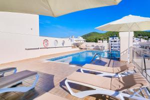 una piscina con due sedie e un ombrellone di Aparthotel Duquesa Playa a Santa Eularia des Riu