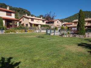 een groene tuin met huizen en een hek bij El Despertar in Boltaña