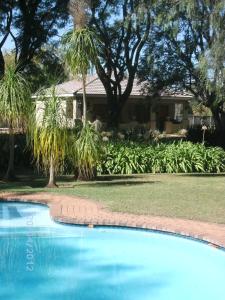 una piscina frente a una casa con palmeras en Farmhouse Lodge, en Newcastle
