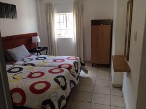 um pequeno quarto com uma cama e uma janela em The Crescent Guesthouses - BnB/Self Catering em Durban