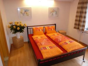 1 Schlafzimmer mit 2 Betten mit orangefarbener Bettwäsche und einer Vase aus Blumen in der Unterkunft Hotel Restaurant Sunnmatt in Aeschi