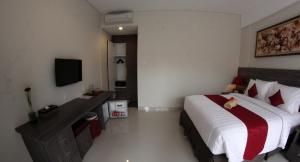 a hotel room with a bed and a television at Puri Kesari Guest House in Sanur