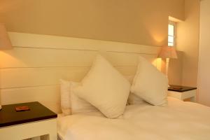 Cama blanca con almohadas blancas y mesa en Quarterdeck 17, en St Francis Bay