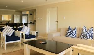 una sala de estar con almohadas azules y blancas en un sofá en Quarterdeck 17, en St Francis Bay