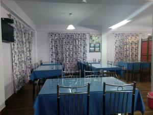 un comedor con mesas azules, sillas y cortinas en Aapas Residency, en Kalimpong